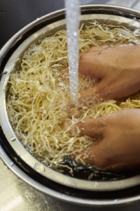 豆腐干に流水をかけながら粗熱を取る。大きめのボウルに入れて流水でもみ洗いしながら、3回ほど水を替える。
