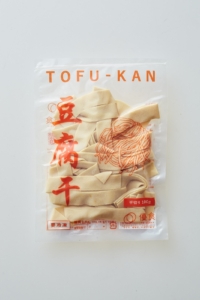 「冷凍豆腐干　平切り」平たい帯状の豆腐干。汁気の多い煮ものや鍋に活用したり、平麺の代わりに使ったりするのがオススメ。
