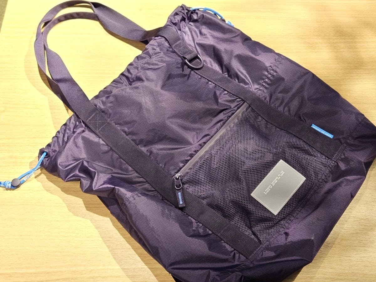 リサイクル断裂防止ナイロン100%を使用し、耐水性も◎。一見機能的なトートバッグというような見た目で、上部の紐を絞ると巾着型に。