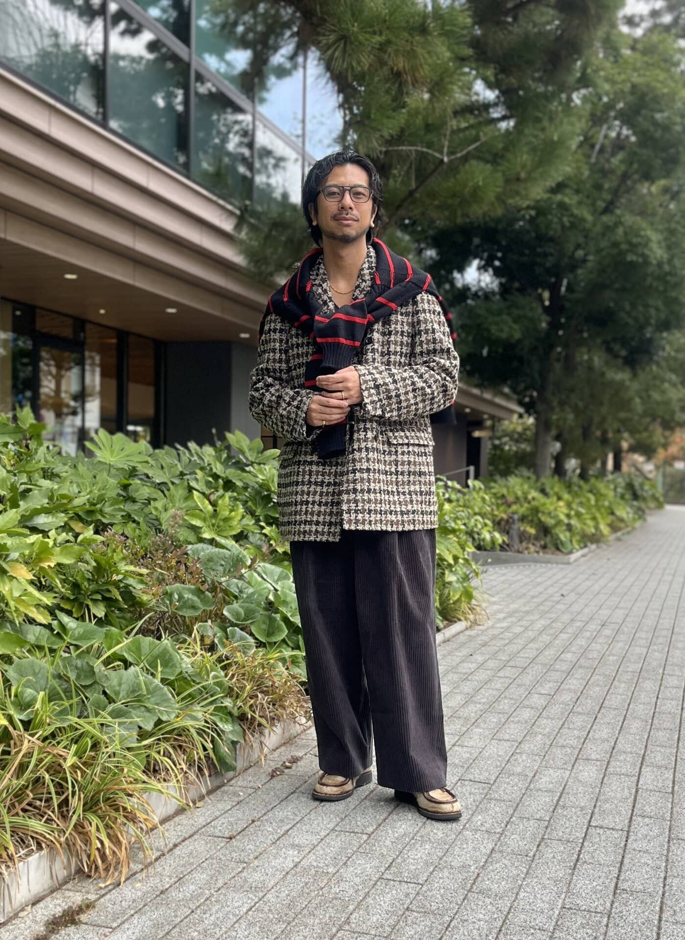 インカミングのエディフィス別注コート、古着のニットとベルト、エディフィスEレーベルのパンツ、肩にかけたガンジウレンスのニット、バディ オプティカルのメガネ、パラブーツのシューズは内田さんの私物