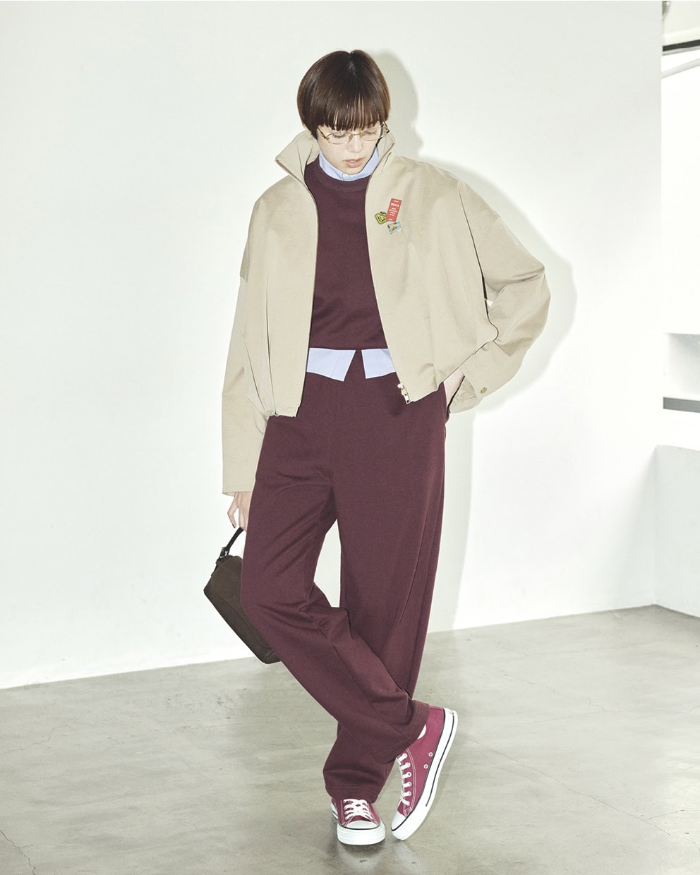 ブルゾン¥72,600（ダブルスタンダードクロージング／フィルム）、スエット¥18,700、パンツ¥29,700（共にロエフ／エイチ ビューティー＆ユース）、中に着たシャツ¥45,1 00（マッキントッシュ／マッキントッシュ 六本木ヒルズ店）、メガネ¥59,290（ミュウミュウ／ルックスオティカジャパン カスタマーサービス）、ブルゾンに付けたピンバッジ各¥500（全てLong Beach OMOTESANDO）、バッグ¥141,900（J＆M デヴィッドソン／J＆M デヴィッドソン カスタマーセンター）、スニーカー¥6,380（コンバース／コンバースインフォメーションセンター）