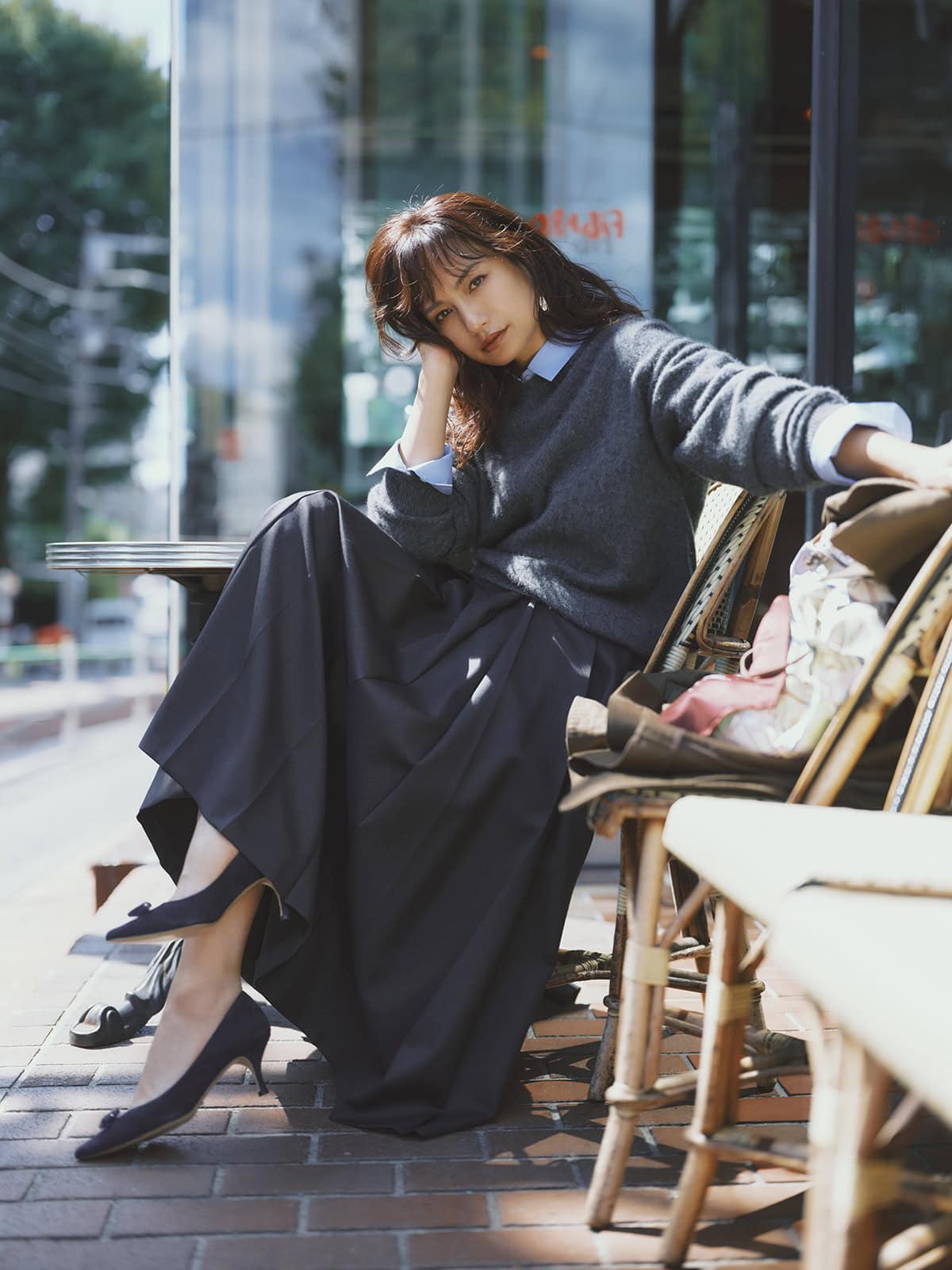 スカート¥80,300、シャツ¥53,900（共にエブール／リトルリーグ インク）、ニット¥66,000（ザ シンゾーン／シンゾーン ルミネ新宿店）、シューズ¥73,700（ネブローニ）、ピアス¥4 6,200（ノアーク／エスケーパーズオンライン）、椅子に掛けたコート¥89,100（カオス／カオス表参道）、バッグ¥25,300（マニプリ）