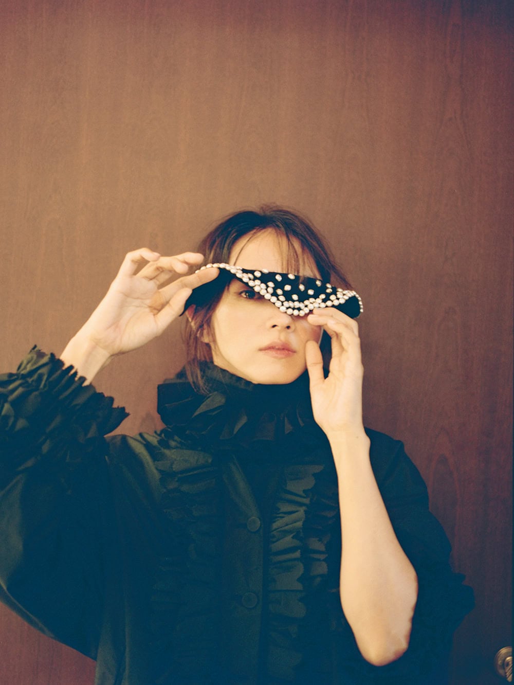 ラッフル付きブルゾン「Michel（ミッシェル）」1,728€、⾸に着けたラッフルカラー ※写真のカットでは着⽤していないシャツとのセット販売「Valerie（ヴァレリー）」1,242€、⼿に持ったガラスパールのつけ襟「Colette（コレット）」459€ ※全て参考価格（全てエコール・ド・キュリオジテ）