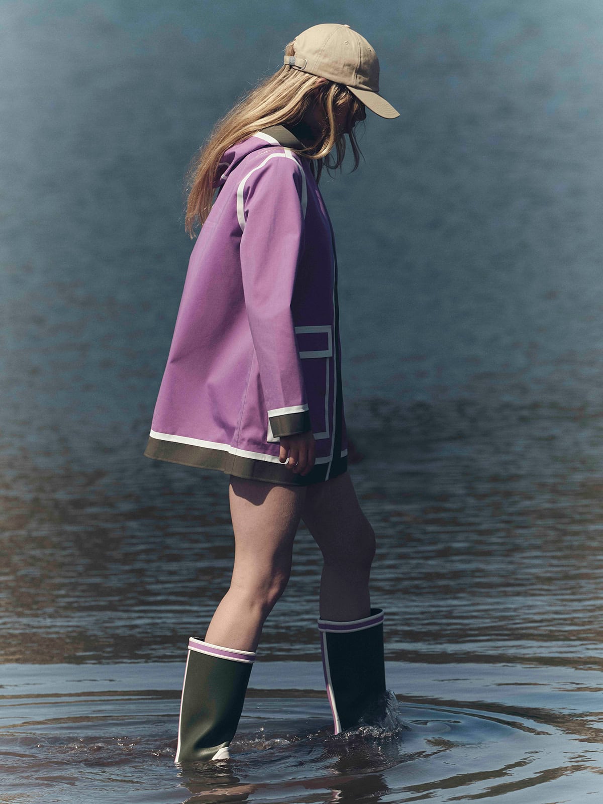 AIGLE×インディア・マダヴィの新作レインコートを着用し水辺を歩くモデルの後ろ姿