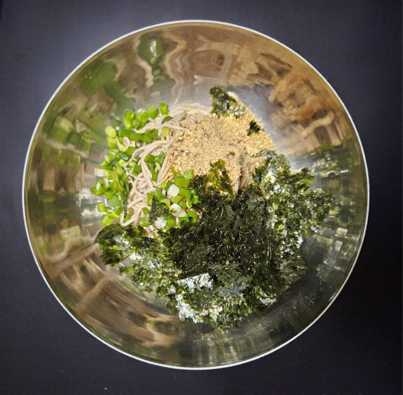 こちらが自作のマッククス。細めのそば(乾麺)を買ってきて茹でて水で洗ってしぼって、ネギ、すりごま、韓国のりに、好きなタレを作ってえごま油をかけて和えるだけ。とっても簡単。タレは醤油、酢、砂糖なんかを適当に混ぜた味が主流だそうですが、面倒くさかったらめんつゆかけたり、オイスターソースを混ぜてみたりしてもいいかも。