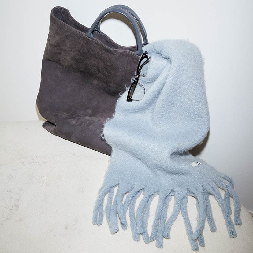 「荷物多めな私にぴったりの大容量トートは、タフなヌバックレザーでガシガシ使える。アイスブルーのストールとの配色バランスがツボ」。エイトンのバッグ、アンヌークのストールとメガネ／全て本人私物