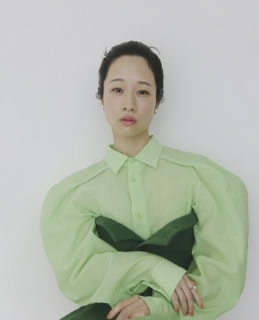 シャツ ¥83,600、上に重ねたトップ ￥55,000、スカート¥85,800（全てイッセイ ミヤケ）、イヤリング 各¥33,000、リング ¥220,000（全てカラットアー／イセタンサローネ トウキョウ）