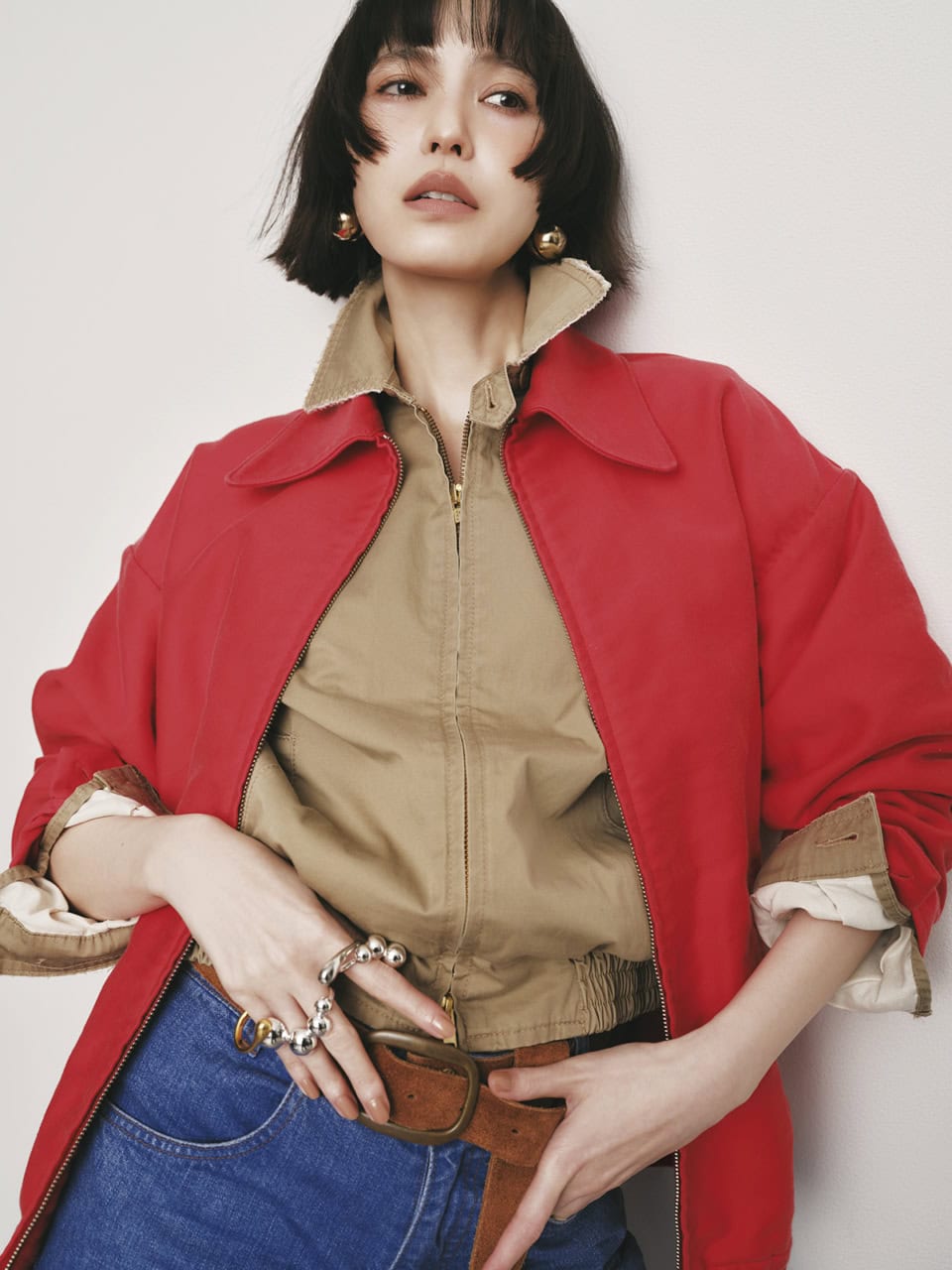 レッドブルゾン¥165,000、ベージュブルゾン¥132,000、デニムパンツ¥77,000、ベルト¥35,200（全てマディソンブルー）、リング右手人さし指¥14,300、ダブルリング中指¥15,400、フィンガーバングル¥32,540（全てソワリー）、シングルピアス 各¥24,200（共にマユ／マユ ショールーム）