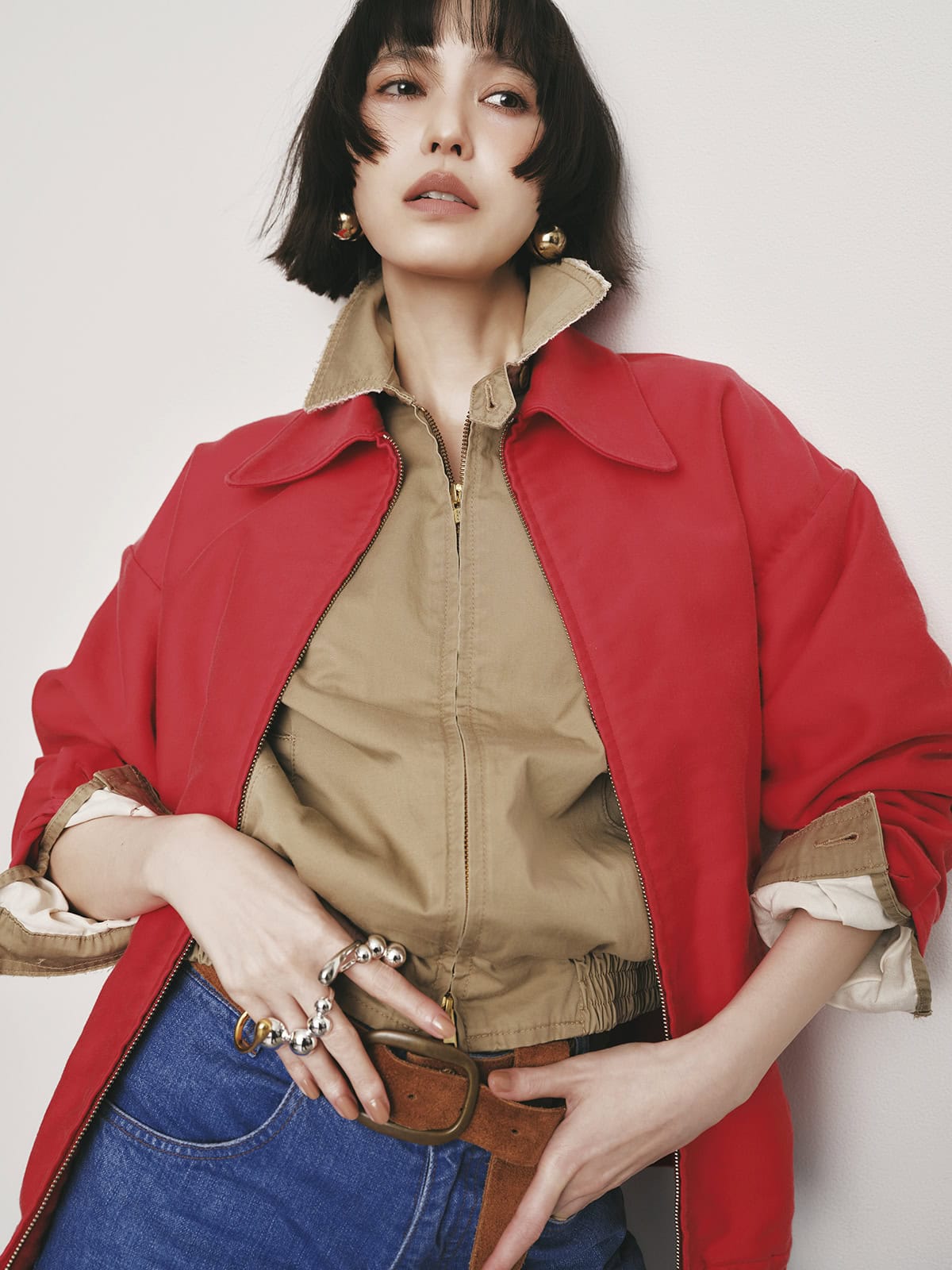 レッドブルゾン¥165,000、ベージュブルゾン¥132,000、デニムパンツ¥77,000、ベルト¥35,200（全てマディソンブルー）、リング右手人さし指¥14,300、ダブルリング中指¥15,400、フィンガーバングル¥32,540（全てソワリー）、シングルピアス 各¥24,200（共にマユ／マユ ショールーム）