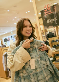 爽やかなブルーのチェックシャツを手に、「やばい！ これもいいかも……」。 「いつもなら無難な色を選んじゃうけど、アウトレットだからこそ冒険できるよね」とこちらを追加購入