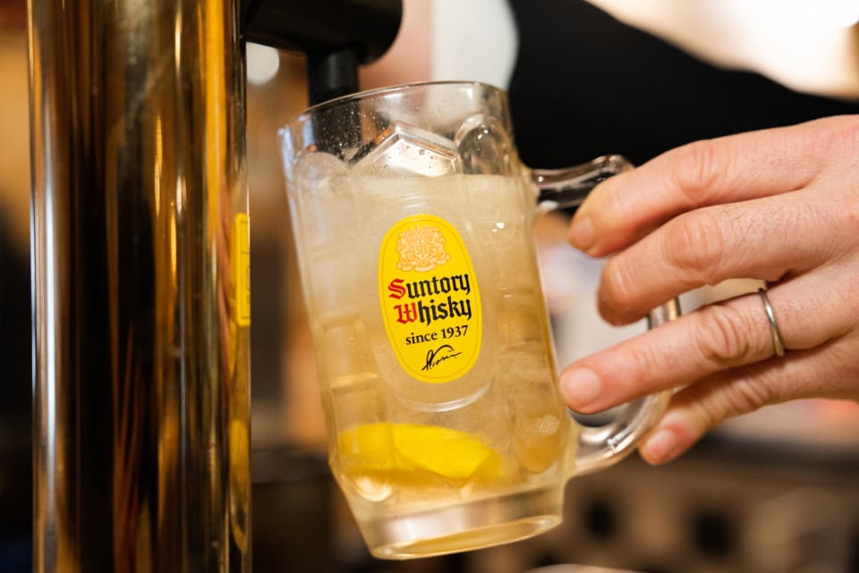 別格角ハイボール、作り方はまず氷を入れる前にレモンを軽く絞るところから始まります。その後、山盛りの氷、ウイスキーの順に入れ、最適温1度の超炭酸を注ぎます。パチパチとはじける泡の粒が小さく、きめ細やか。これが喉を通る瞬間の、あの「くぅ〜っ!」という刺激の正体でした。