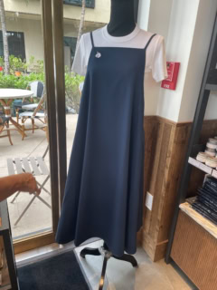 【カカアコ・コウラ店】ストンと落ち感のある素材のエプロンは前から見たらAラインドレスのようなルックス。バッグがクロスになって、レディな雰囲気。エプロン65ドル（日本円で約10,400円）