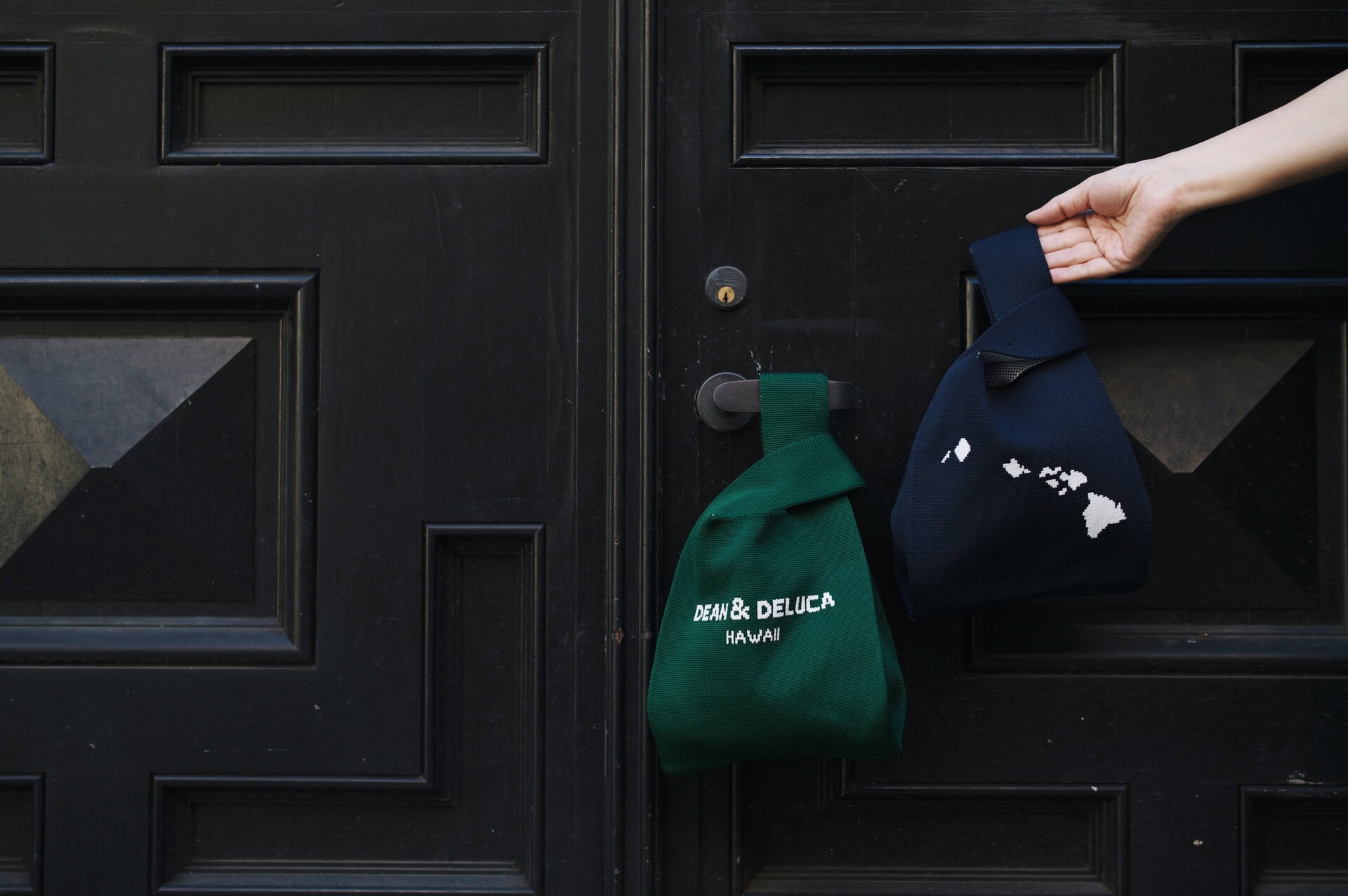 【カカアコ・コウラ店】コウラ店の限定バッグはこちら。ニット素材でコンパクトになるので、旅行などにも便利です。ネイビーはハワイ諸島が、グリーンは裏面がパイナップル柄。各30ドル（日本円で約4,800円）