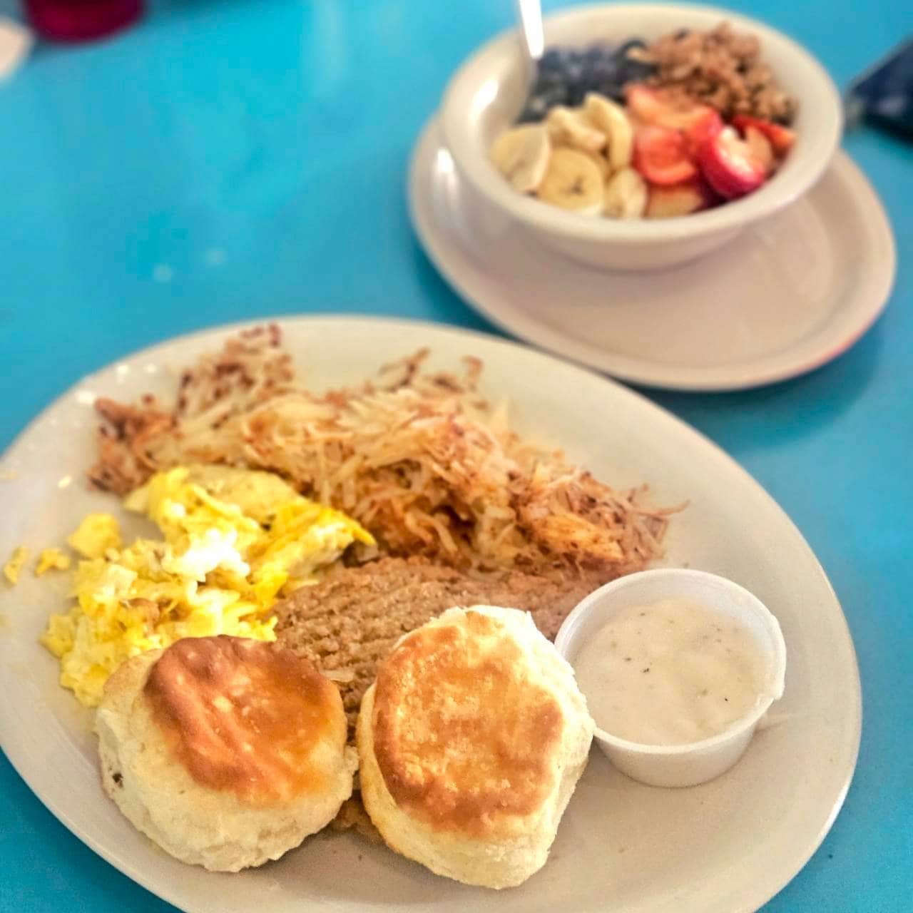 【The Arcade Restaurant】こちらはカントリーフライドステーキ(COUNRTY FRIED STEAK)14.25ドル(日本円で約2,351円)。2個の卵をスクランブルにしてくれて、グリッツかハッシュブラウン(写真はこっち)、ビスケット。メインは牛肉に小麦粉の衣をまぶして揚げ、ホワイトグレービーソースをかけた、アメリカ南部料理の定番フライドステーキです。あ、奥はヘルシーな観光局美女が食べていたアサイーボウル的なものです。
