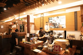 お店の入口近くでは、低い椅子に座って麺を茹でる料理人の姿が！
