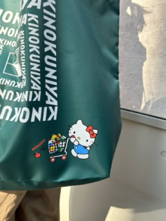 紀ノ国屋ロゴを大きくあしらったシンプルなデザインに、買い物中のキティを添えて。