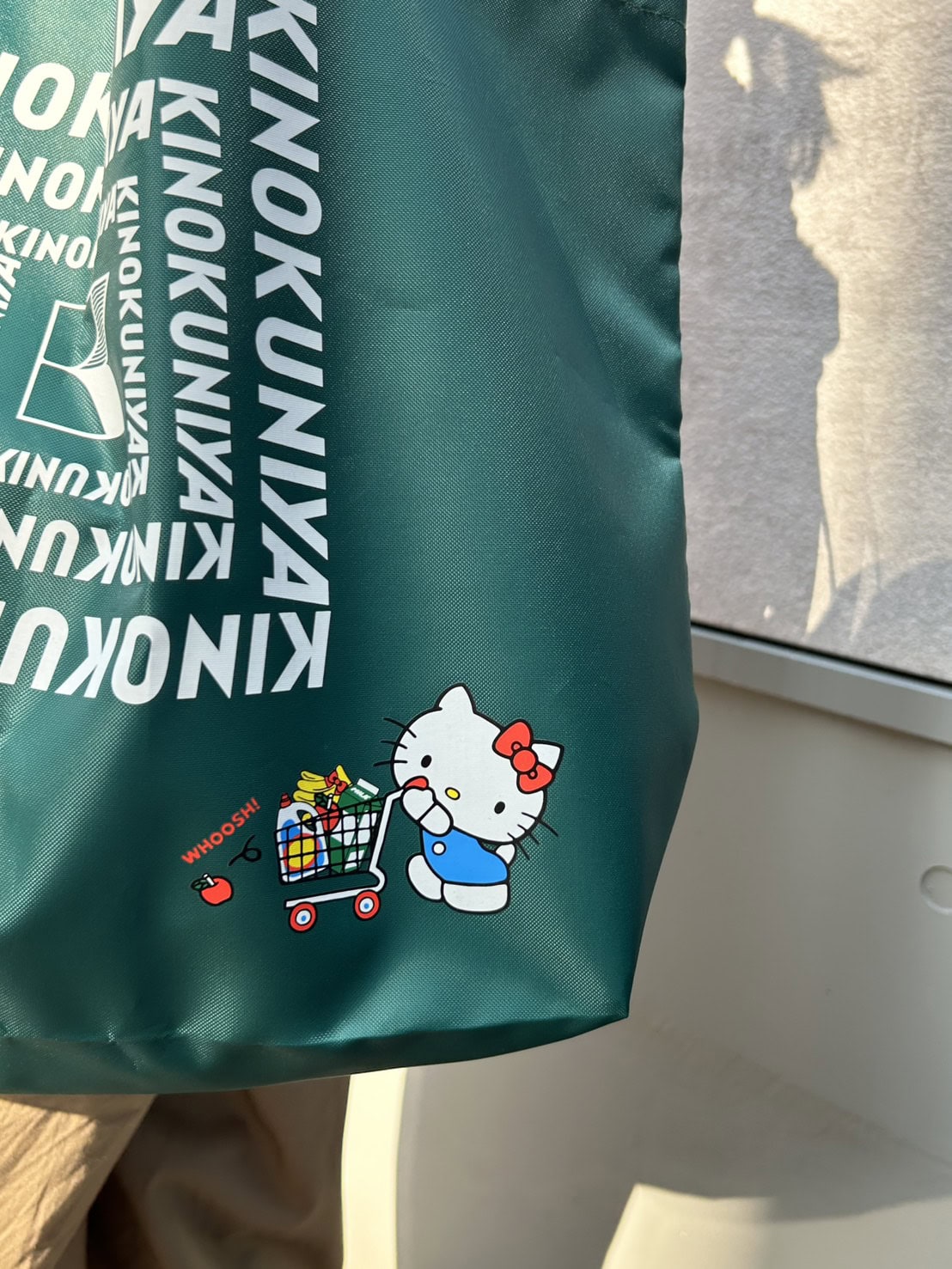 紀ノ国屋ロゴを大きくあしらったシンプルなデザインに、買い物中のキティを添えて。
