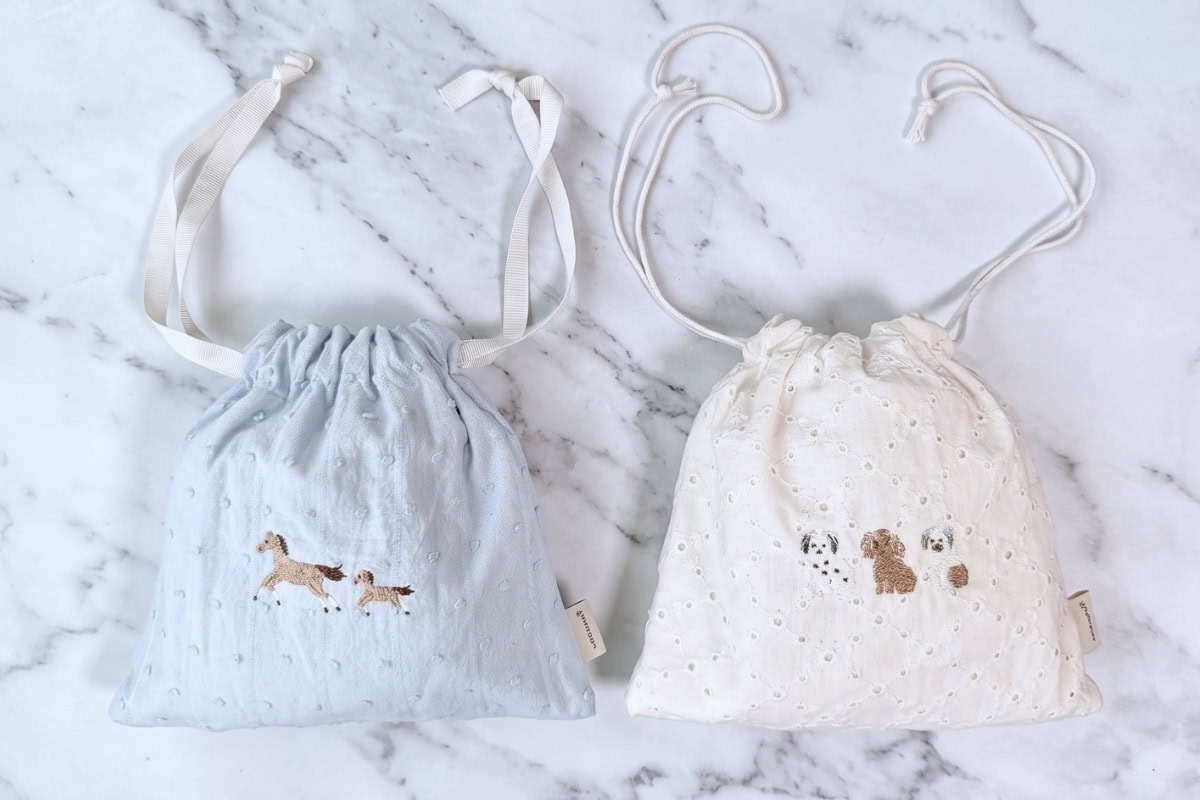 開閉がスムーズで見た目以上に入るドローストリング仕様。洗練されたオリジナル刺繍が愛らしく、見るたびに気分が高まります。汚れたらサッと洗える布製だから、日常も非常時もクリーンに活躍！